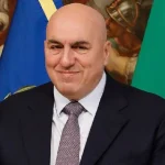 Гвидо Крозетто улыбается на фоне флагов Италии и Европейского союза