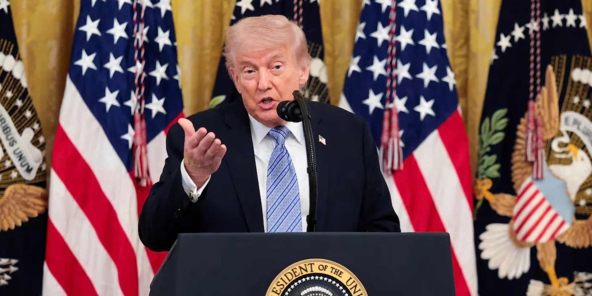 Дональд Трамп выступает за трибуной на фоне американских флагов
