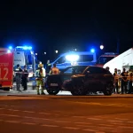 Ночная сцена с полицией, пожарными и автомобилем на улице Берлина