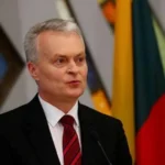 Президент Литви Гітанас Науседа виступає біля мікрофона на тлі національних прапорів