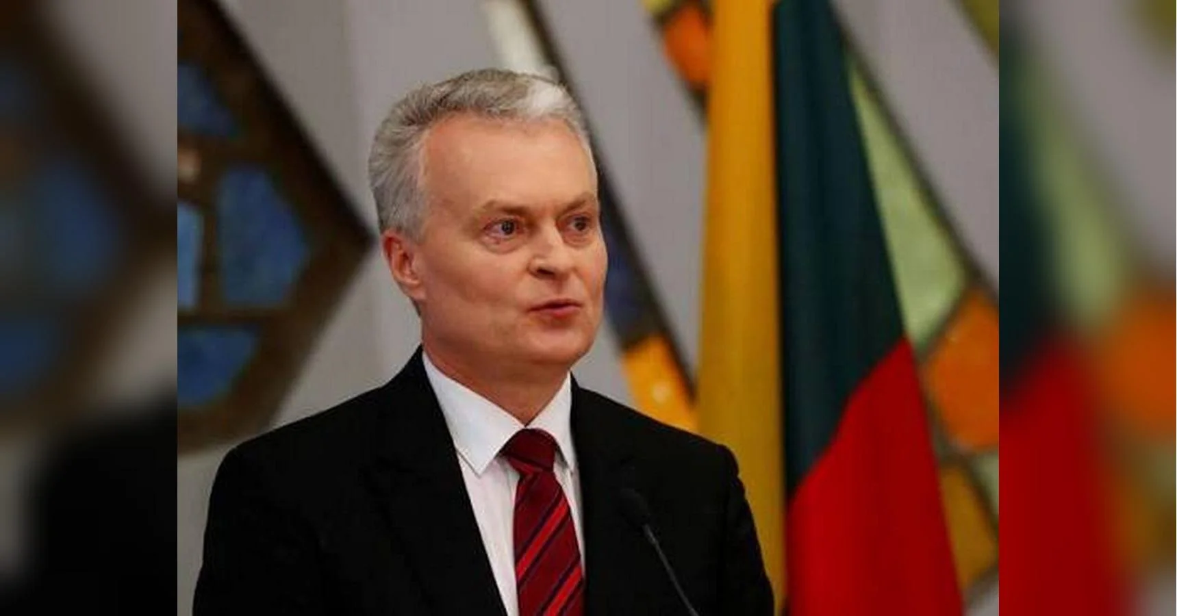 Президент Литви Гітанас Науседа виступає біля мікрофона на тлі національних прапорів